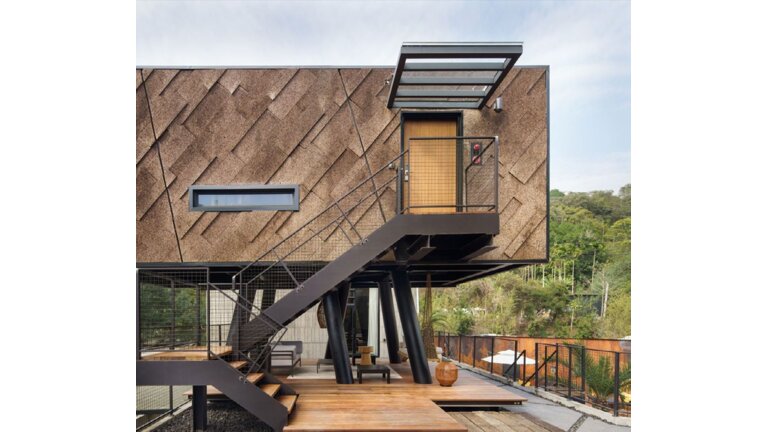 Modernes Haus auf Stelzen mit Korkfassade, Terrasse.